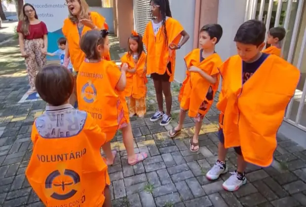 Crianças vestem os coletes de voluntários da Defesa Civil no combate à dengue